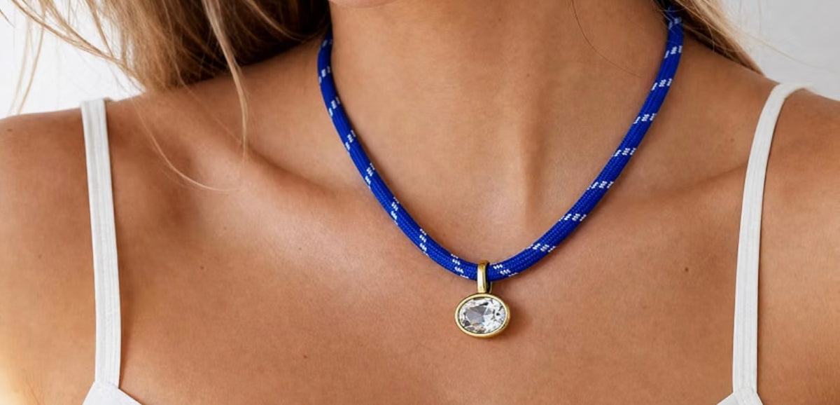 Brilliant oval clear crystal in a gold-tone bezel setting on a patterned blue woven paracord.